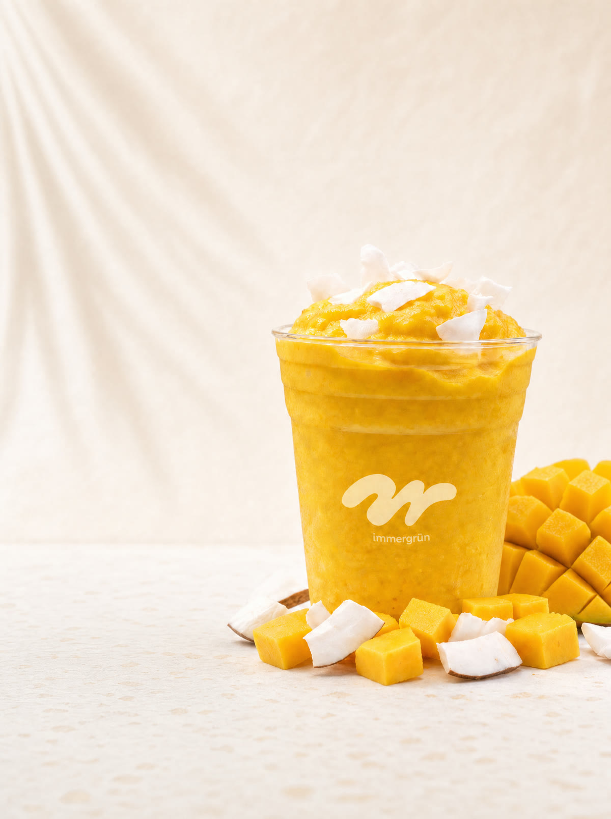 Mango-Kokos-Smoothie im immergrün-Becher mit frischer Mango